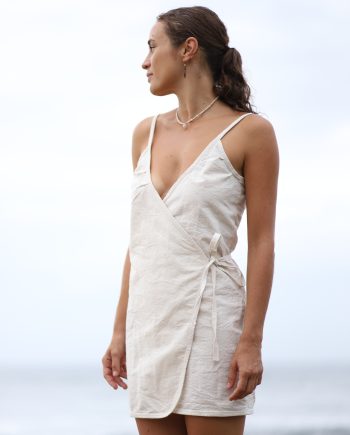 Exude allure with the Higher Himalayan Wrap Dress, where eco-friendly fashion meets seductive design. This hemp wrap dress features a flattering v-neckline and an adjustable tie waist for a custom fit, complemented by delicate spaghetti straps and a playful hemline for a sultry yet elegant look. The natural texture of the hemp fabric, in its pure off-white color, adds an earthy charm to this versatile piece.