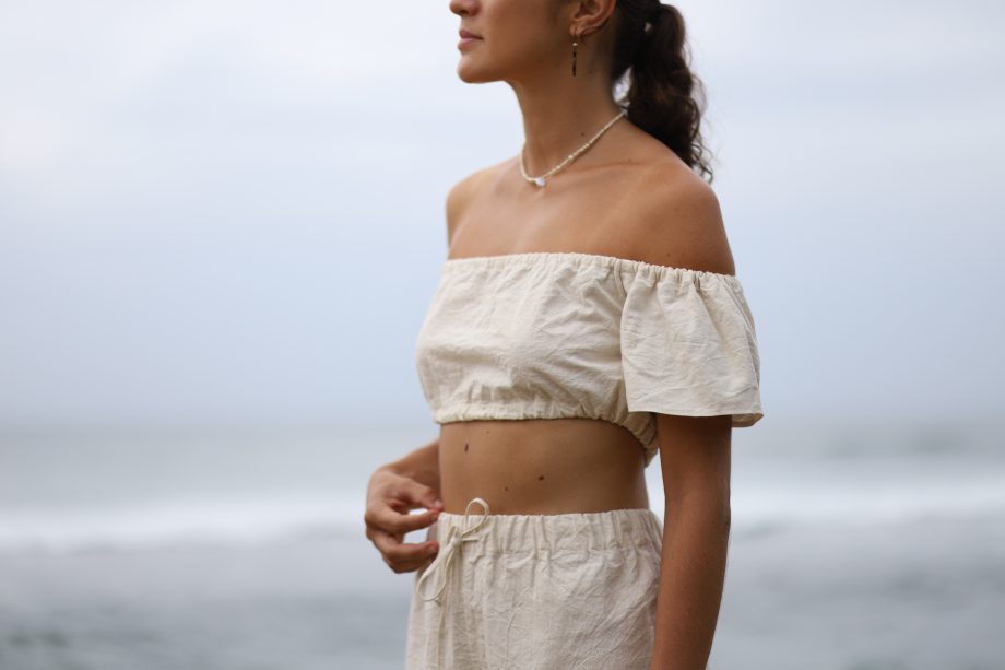 Higher Himalayan's 'Q Top' offers a blend of bohemian charm and eco-friendly fashion. This off-shoulder top, crafted from organic Himalayan hemp, features a ruffled neckline that exudes a playful yet elegant vibe. Its cropped cut and breezy fit encapsulate a free-spirited aesthetic while showcasing sustainable luxury.